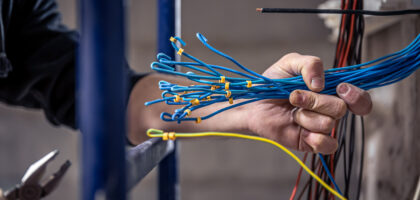 male electrician works switchboard with electrical connecting cable scaled