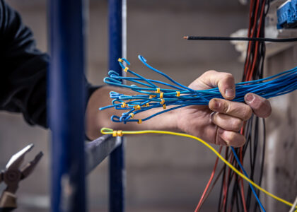 male electrician works switchboard with electrical connecting cable scaled